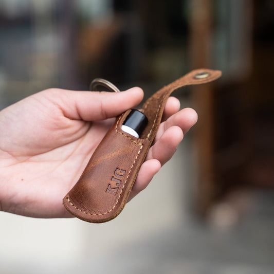 Keychain lip balm holder featuring button snap closure. Made with full-grain American leather. Customize with your initials. Makes for the perfect gift or stocking stuffer. Available in black or brown leather.